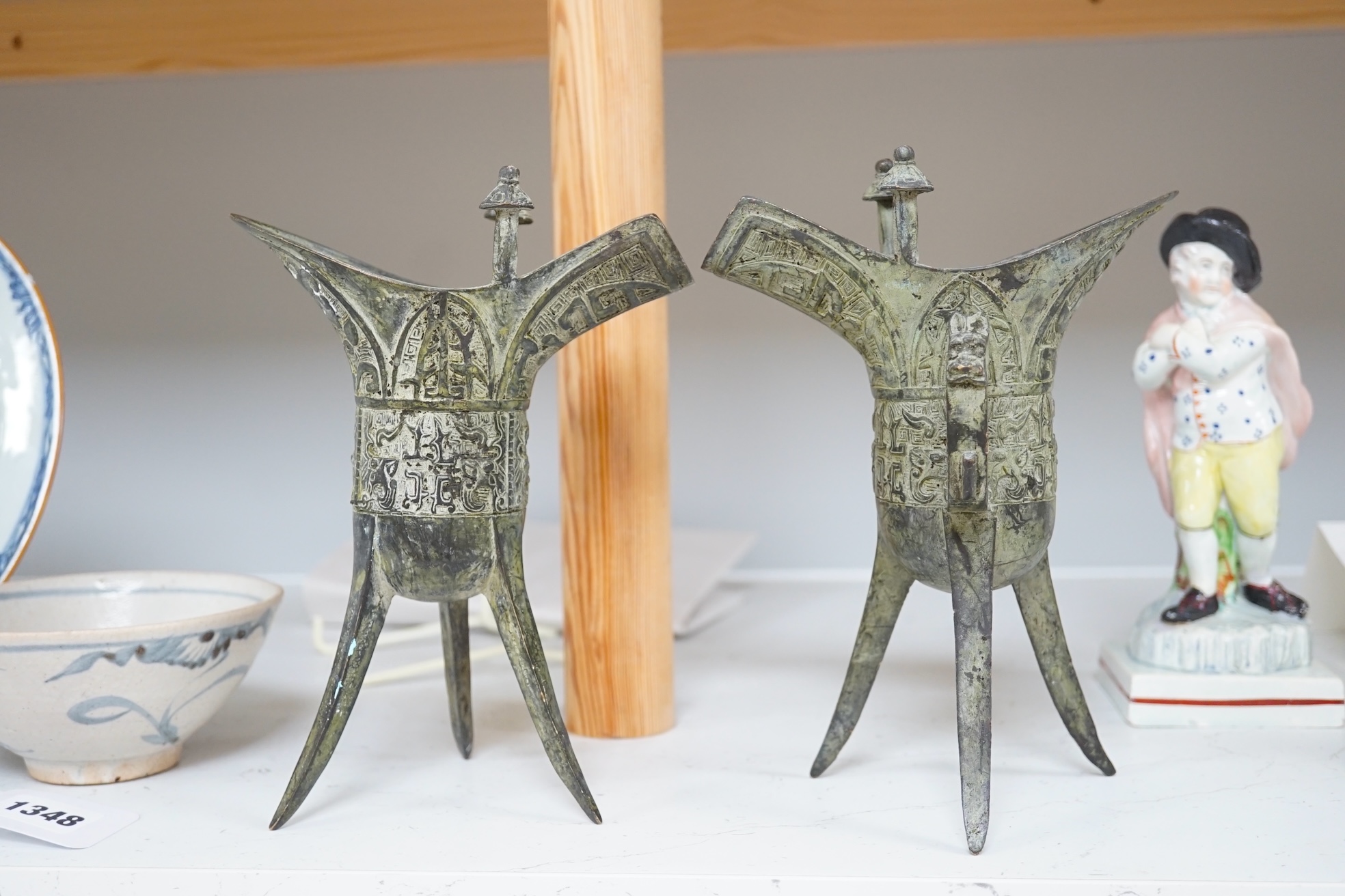 A pair of Chinese archaistic bronze vessels on tripod legs, jue, 20.5cm high. Condition - fair.